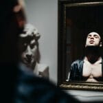 Zamyślony mężczyzna patrzy na swoje odbicie w lustrze