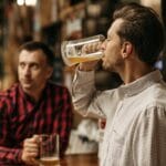 Dwaj mężczyźni piją piwo z kufli w przytulnym pubie