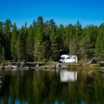 Kamper nad spokojnym jeziorem z odbiciem lasu w Troms latem