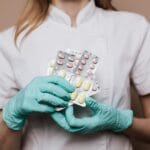 Lekarz w rękawiczkach trzyma blistry z tabletkami kardiologicznymi